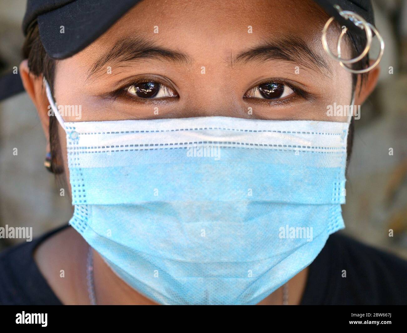 Malay ragazza con cappello nero da baseball indossa una maschera chirurgica monouso durante la pandemia del virus corona 2019/20 e pone per la fotocamera. Foto Stock