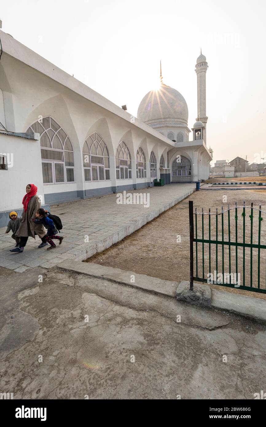 Una donna musulmana cammina con due bambini al famoso santuario di Hazratbal a Srinagar in Kashmir Foto Stock