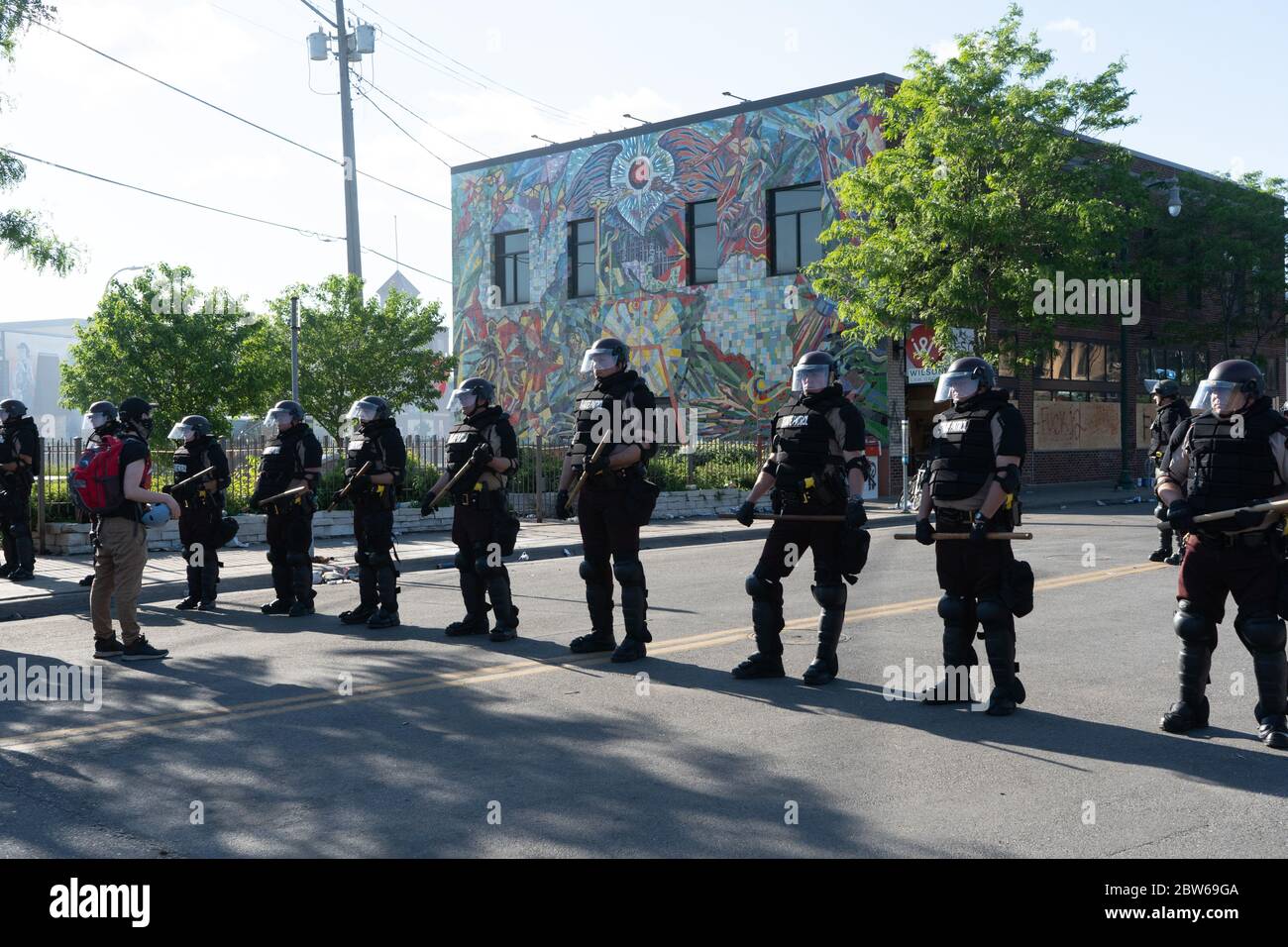 uomo che affronta ufficiali di polizia di pattuglia dello stato in piedi di guardia contro le rivolte di minneapolis e di controllo dimostranti e manifestanti con club Foto Stock