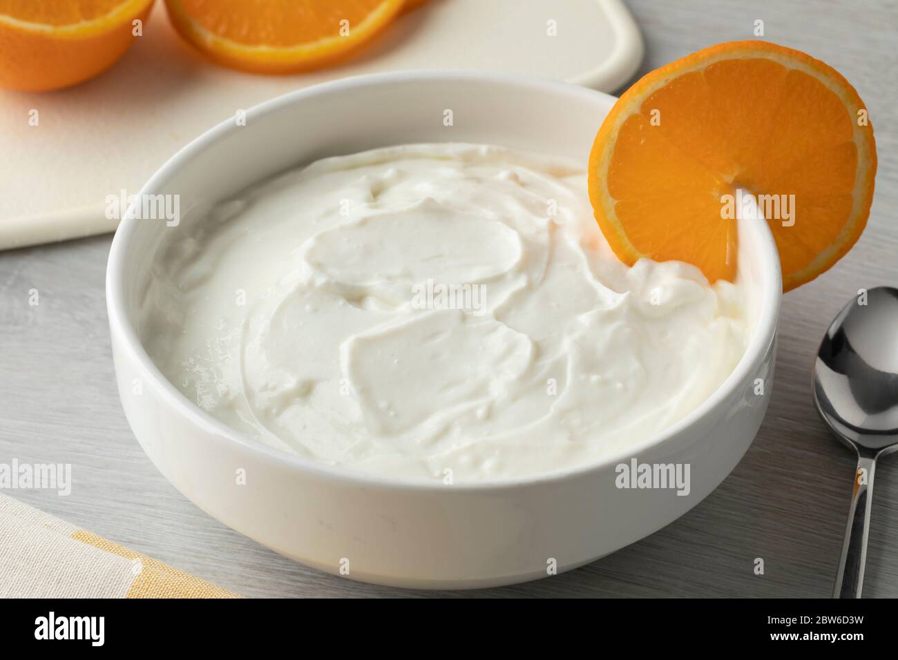 Ciotola con yogurt fatto in casa e una fetta di arancia da vicino Foto Stock