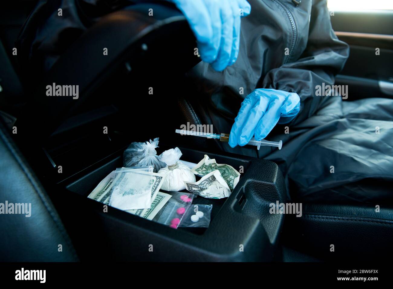 polizia in guanti ispezionare l'auto del dragdiller e trovare droghe Foto Stock