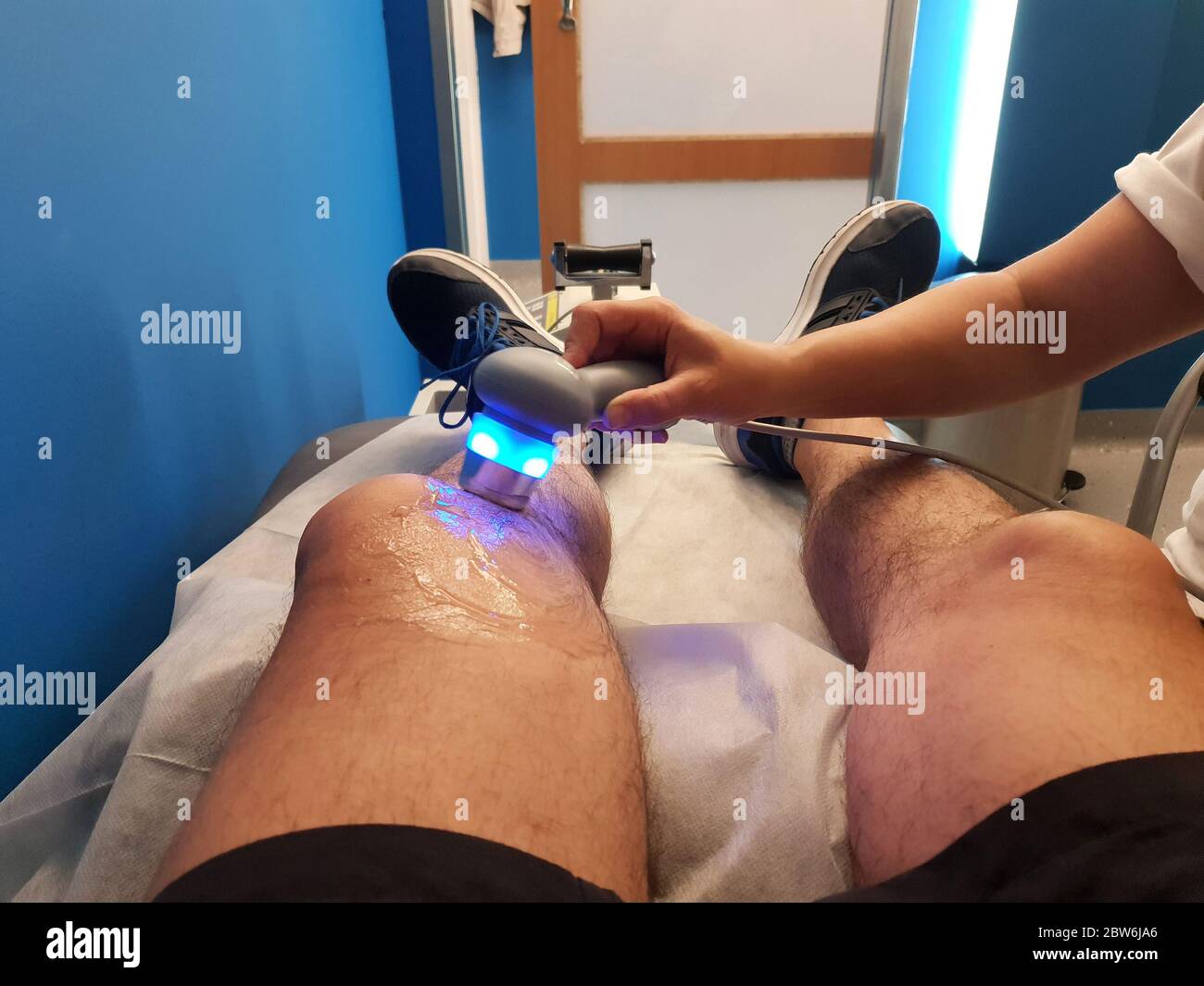 Il fisioterapista sta applicando la terapia a ultrasuoni sulle lesioni al ginocchio con il trasduttore per la testa a ultrasuoni Foto Stock