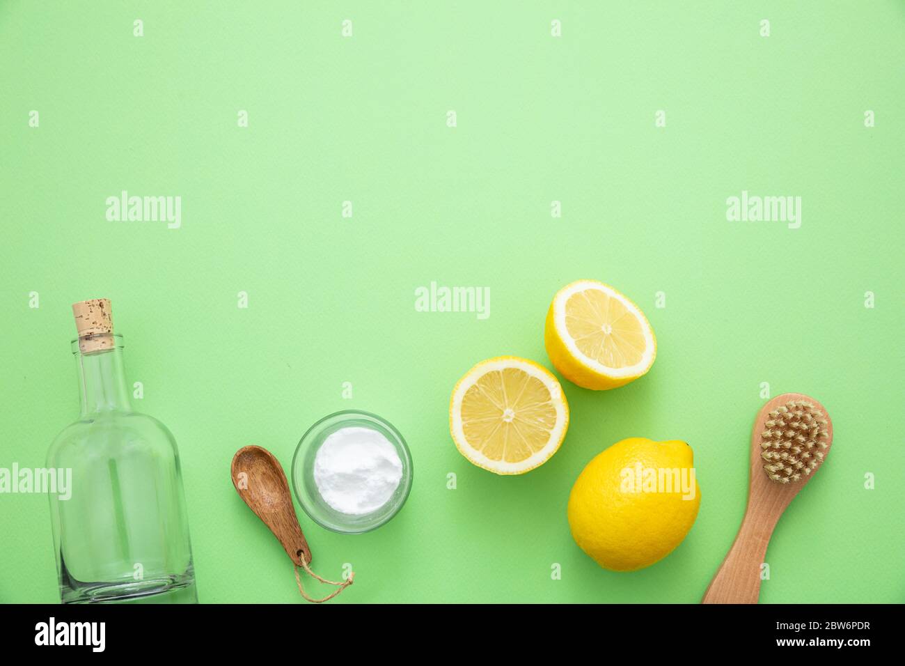 Pulizia ecologica sfondo domestico. Prodotti per la pulizia in casa sicuro non tossico piatto lay, bicarbonato di sodio, aceto di limone e fiori freschi su verde colore ba Foto Stock