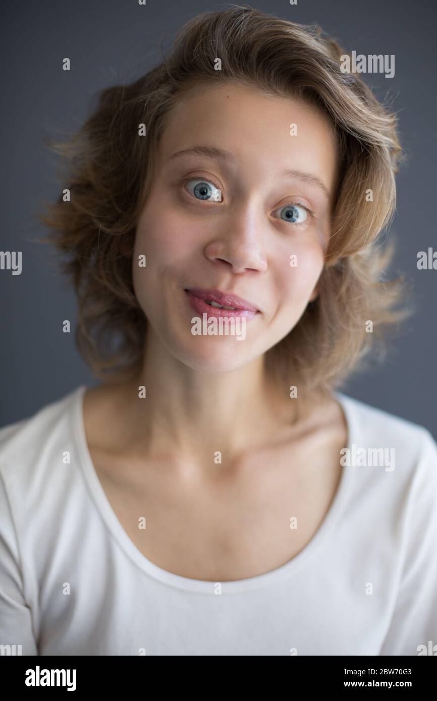 Ritratto di giovane gioiosa donna che guarda in macchina fotografica con gli occhi larghi Foto Stock