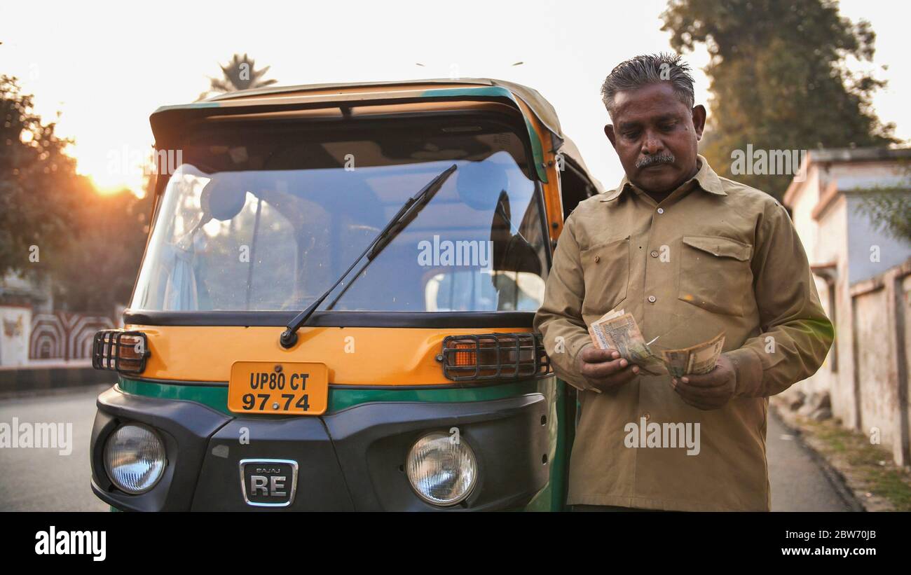 Agra, India - 12 dicembre 2018: L'uomo indiano del driver del tuk-del rickshaw auto racconta i soldi. Foto Stock