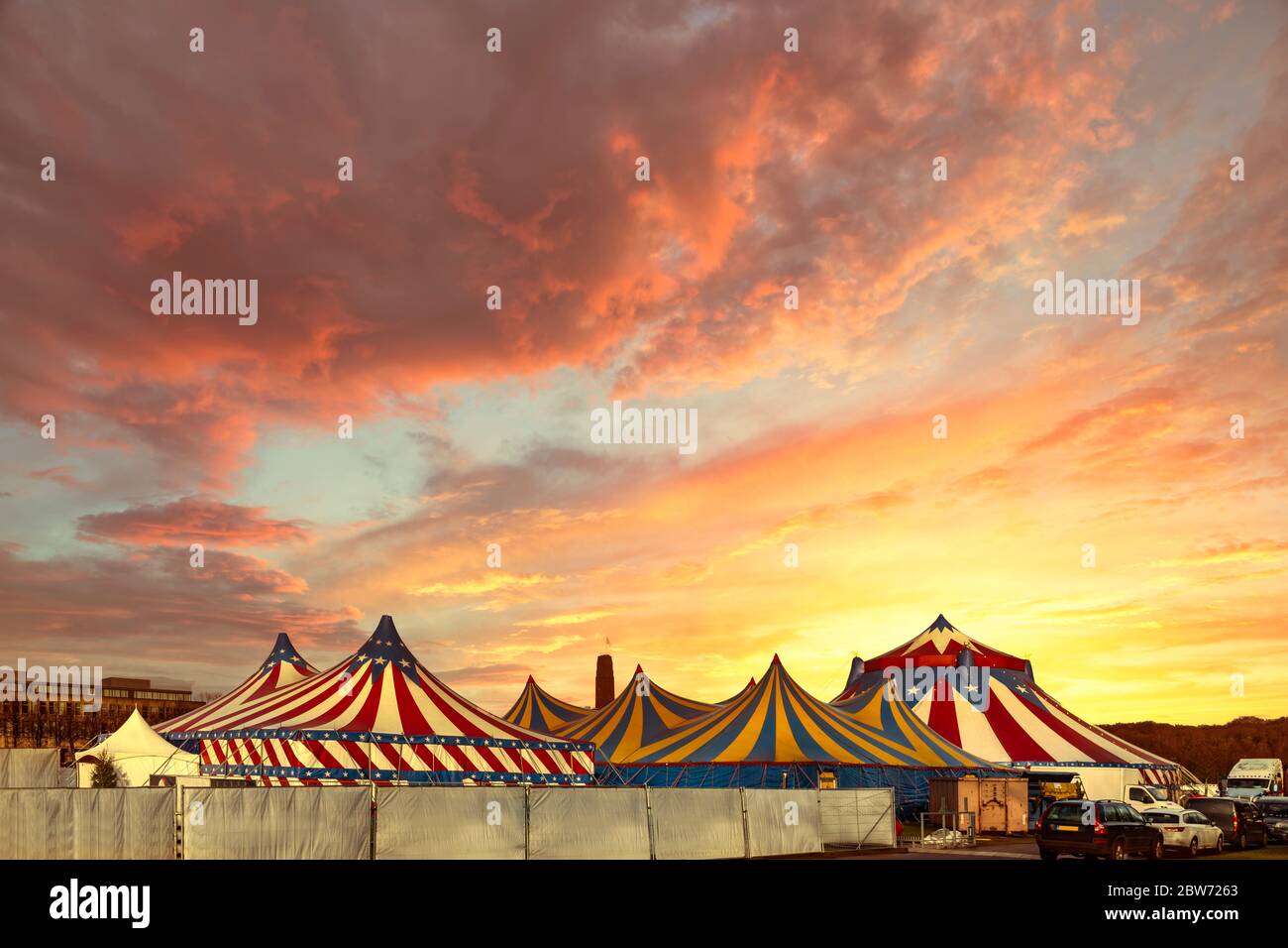 Tende rosse e bianche del circo sormontate con una copertura stella bleu contro un cielo azzurro soleggiato con nuvole Foto Stock