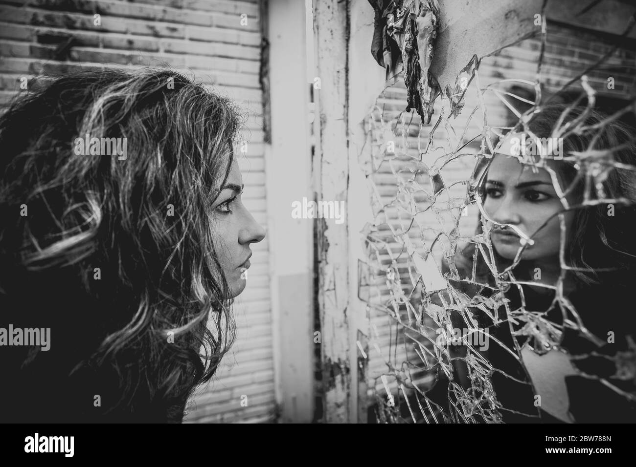Una donna davanti a uno specchio rotto Foto Stock