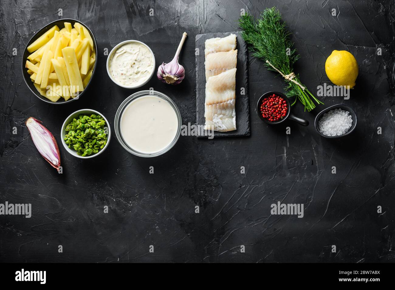 Pesce e patatine tradizionali ingredienti ricetta filetti di merluzzo crudo su pastella di ardesia di pietra, potatoe, salsa tartaro, piselli minati, limone, scalogno, menta, g Foto Stock