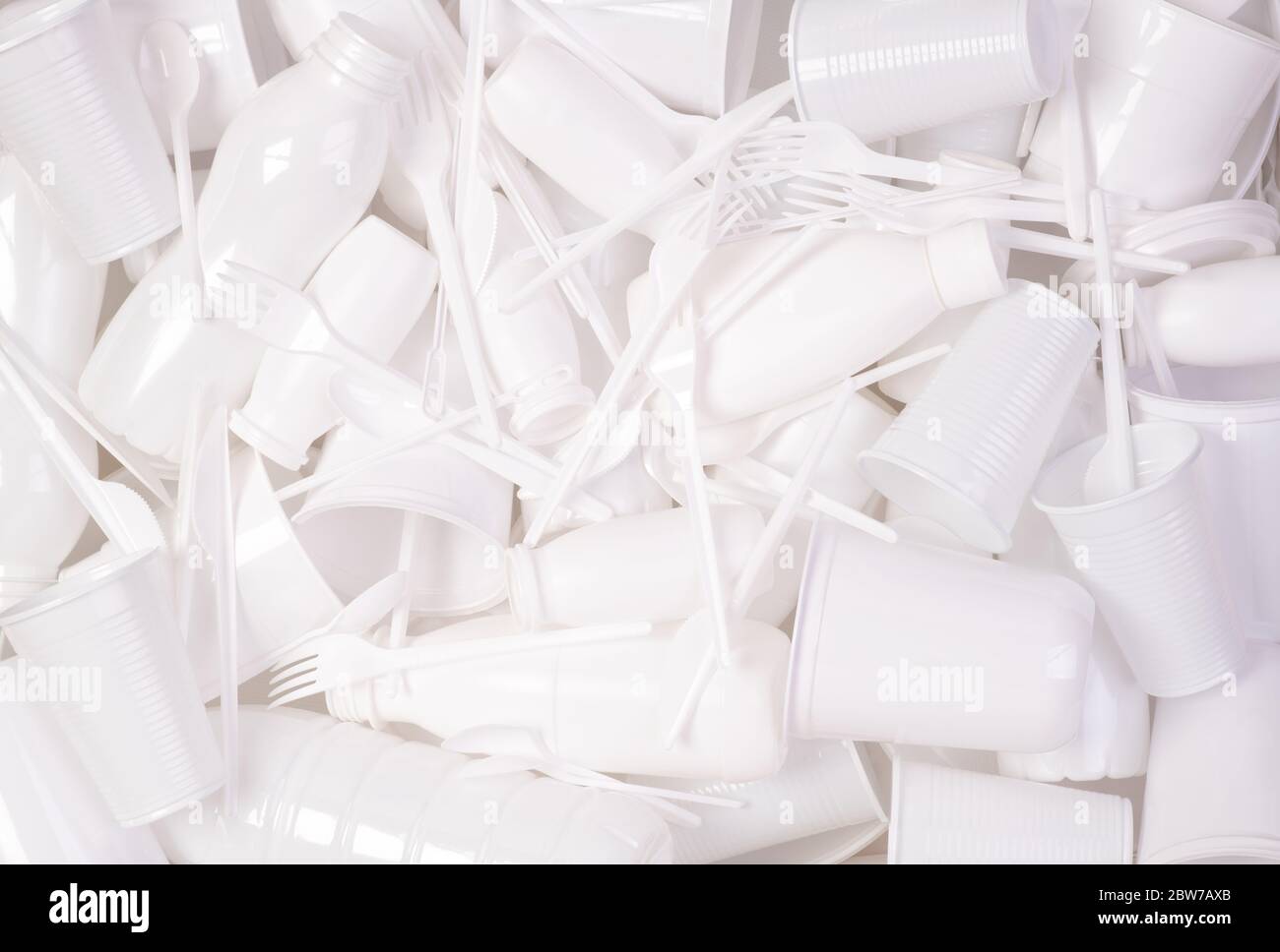 Oggetti in plastica monouso bianchi, come bottiglie, tazze, forcelle e cucchiai, che causano inquinamento ambientale Foto Stock