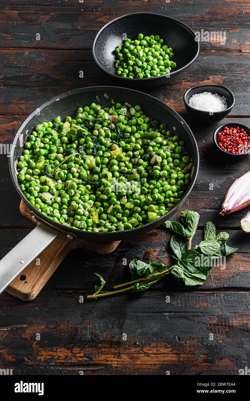 piselli con funghi al keto ingredienti in padella e piselli in ciotola con pepe di scalogno alla menta e vista sul piano del sale sul tavolo in legno del vecchio pub verticale. Foto Stock