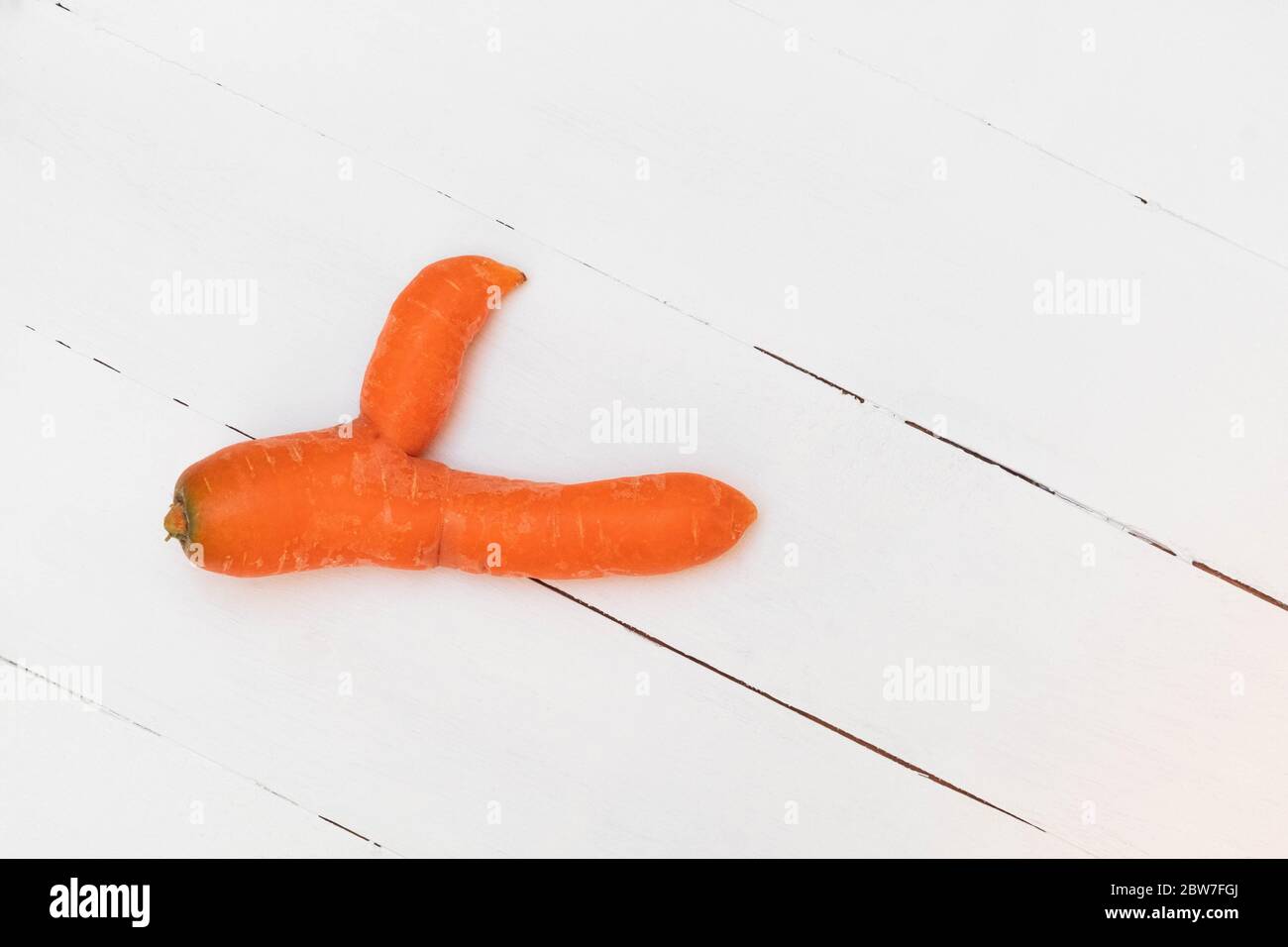 Brutto carota mostra pollice fino a sostegno dei rifiuti alimentari tendenza. Immagine con copia spazio, vista dall'alto Foto Stock