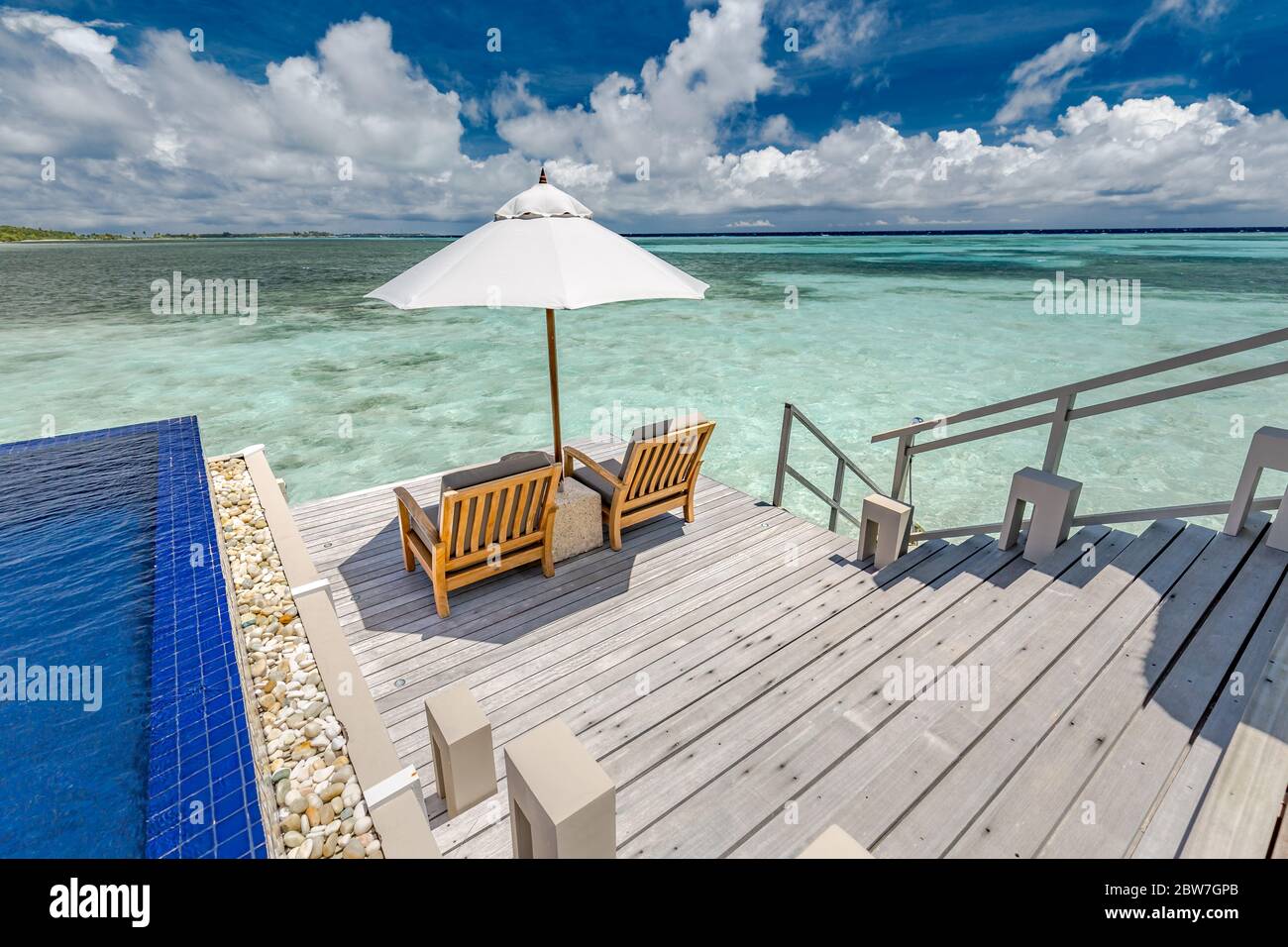 Piscina di lusso in villa sull'acqua con sedie a sdraio e ombrellone. Fantastiche vibrazioni estive, vista mare e lussuosa scena di coppia. Paradiso tropicale Foto Stock
