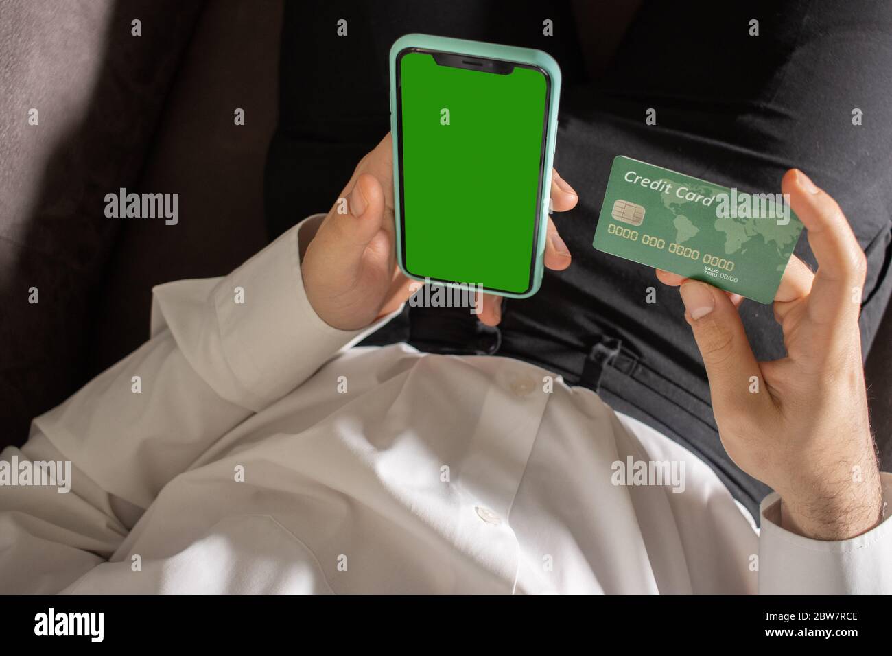 Uno smartphone nero e una carta di credito nelle mani di un uomo Foto Stock