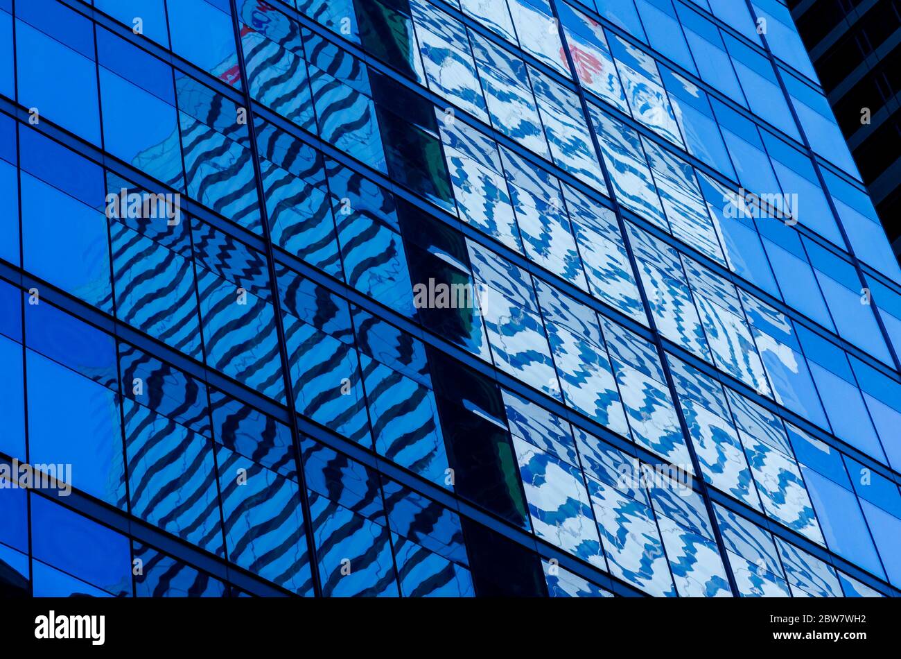 La torre dell'ufficio in vetro e acciaio riflette il cielo e una torre dell'ufficio adiacente Foto Stock