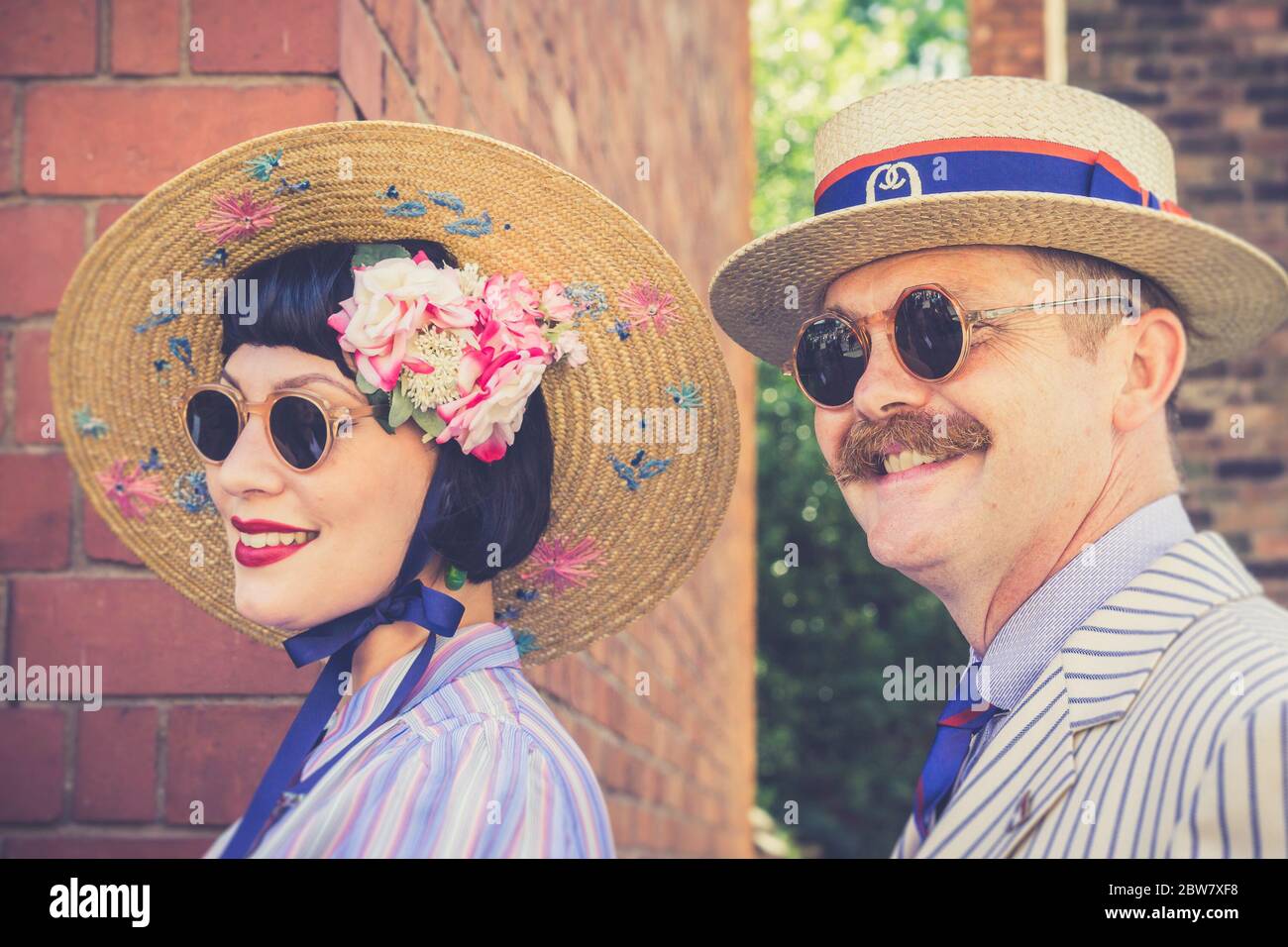 Primo piano della coppia vintage britannica degli anni '40, vestita con eleganza in un ambiente di moda anni '40 sorridente all'aperto durante l'evento estivo della seconda guerra mondiale degli anni '40, nel Regno Unito. Foto Stock