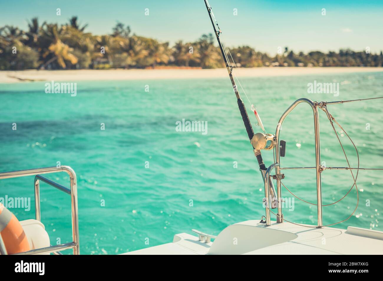 Primo piano di una mulinello da pesca sulla barca, isola tropicale mare con tempo soleggiato. Sport esotico e attività ricreative Foto Stock