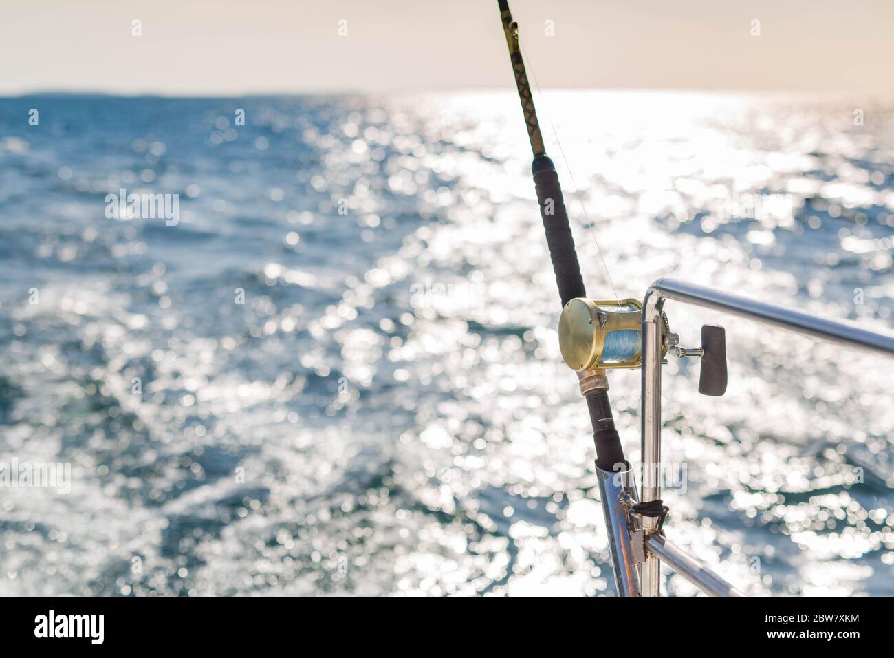 Primo piano di una mulinello da pesca sulla barca, isola tropicale mare con tempo soleggiato. Sport esotico e attività ricreative Foto Stock
