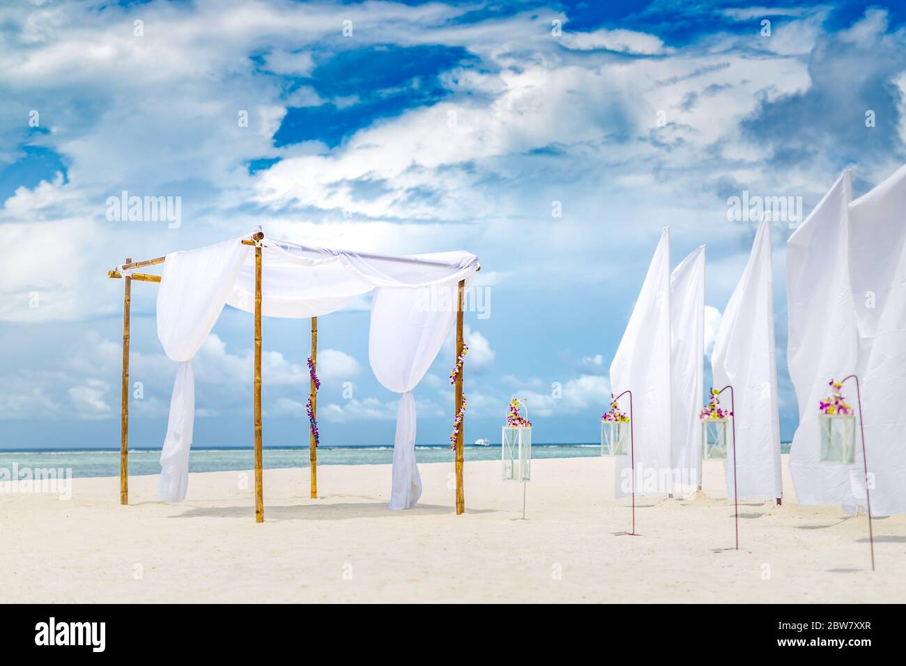 Cerimonia di matrimonio romantica sulla spiaggia. Esotica destinazione cerimonia nuziale, decorazione di lusso, candele e fiori sotto arco di nozze, luna di miele Foto Stock