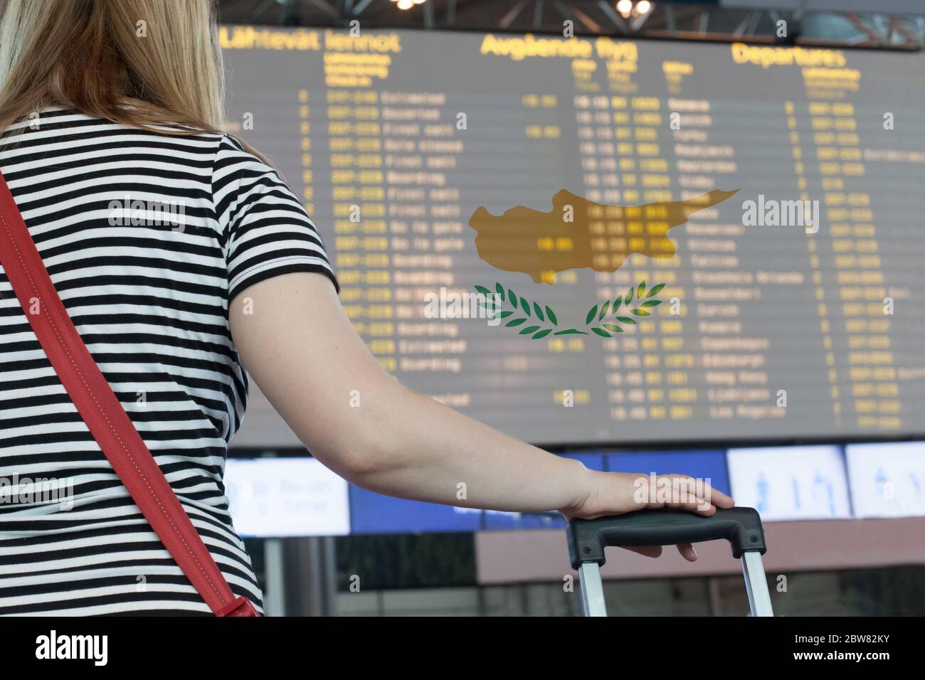 Donna guarda il tabellone di valutazione all'aeroporto. Selezionare un paese Cipro per viaggi o migrazioni. Foto Stock