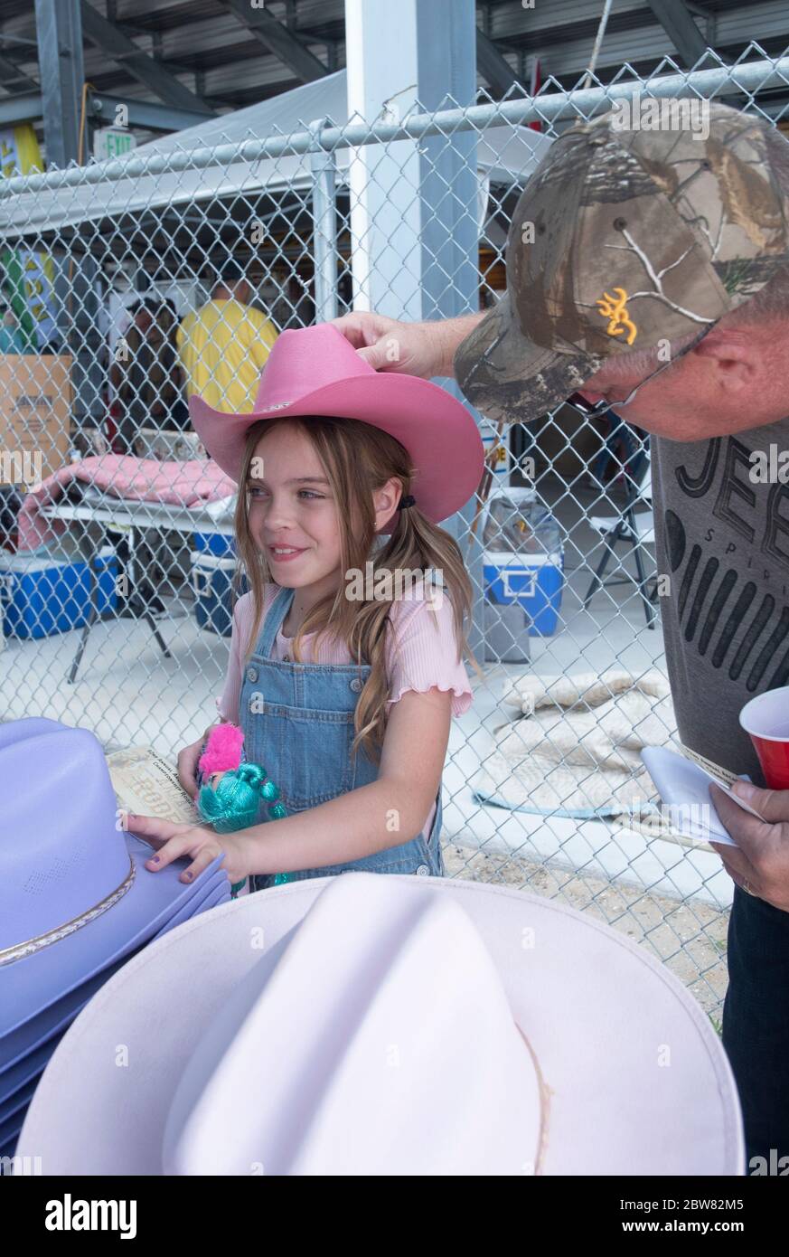 Jeff Leedy posiziona un cappello sulla testa di sua figlia Chandler ferri prima del rodeo. Foto Stock