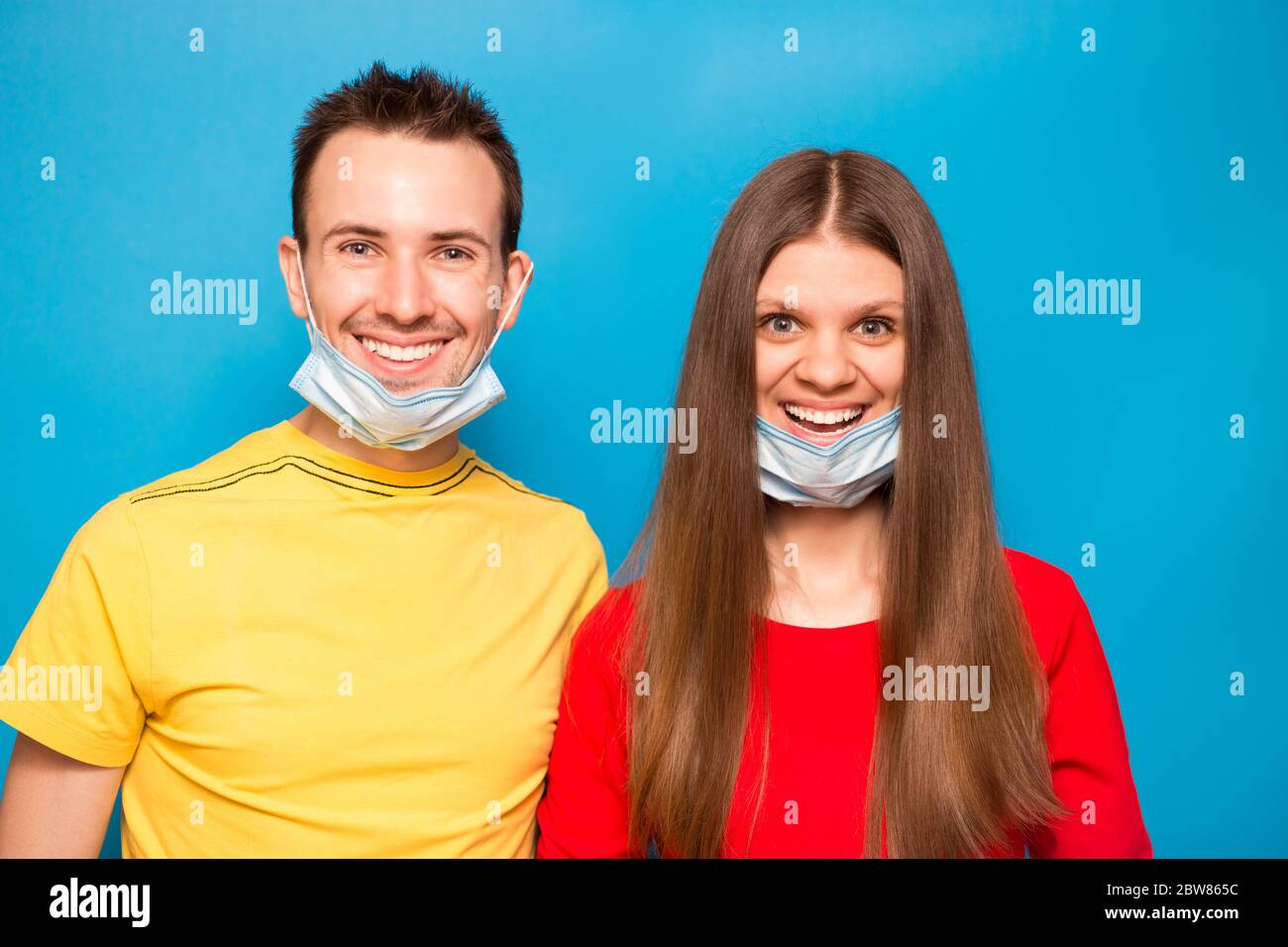 Happy Love coppia rimuovere maschera protettiva isolata su sfondo blu. Fine della pandemia di coronavirus, quarantena, autoisolamento. La crisi del Covid-19 è finita Foto Stock