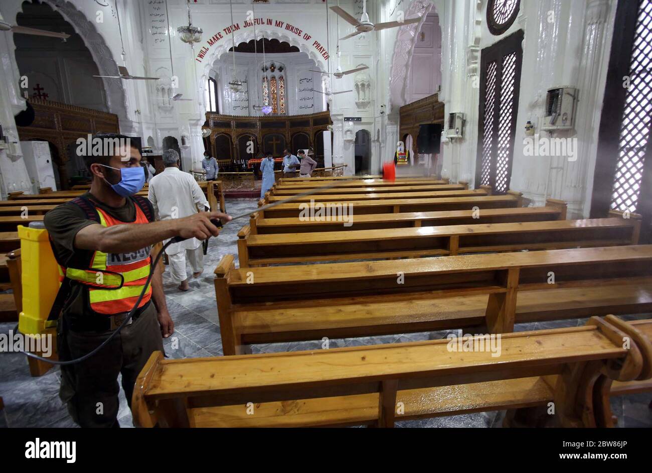 Soccorso 1122 lavoratori spruzzano acqua di cloro in tutte le aree della Chiesa di tutti i Santi per la disinfezione come misura preventiva contro il coronavirus (COVID-19), a Peshawar Sabato, 30 maggio 2020. Il numero di casi confermati di COVID-19 in Pakistan è salito a 66,457 il sabato dopo la conferma di nuove infezioni nel paese. Foto Stock