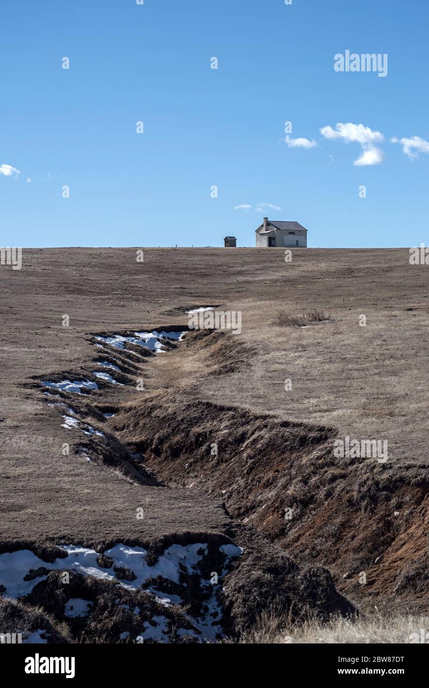 Old Farm Building in Colorado Pastureland adiacente a Glendale Open Space, a sud di Denver, Colorado, con una profonda erosione Scar in the Foreground Foto Stock