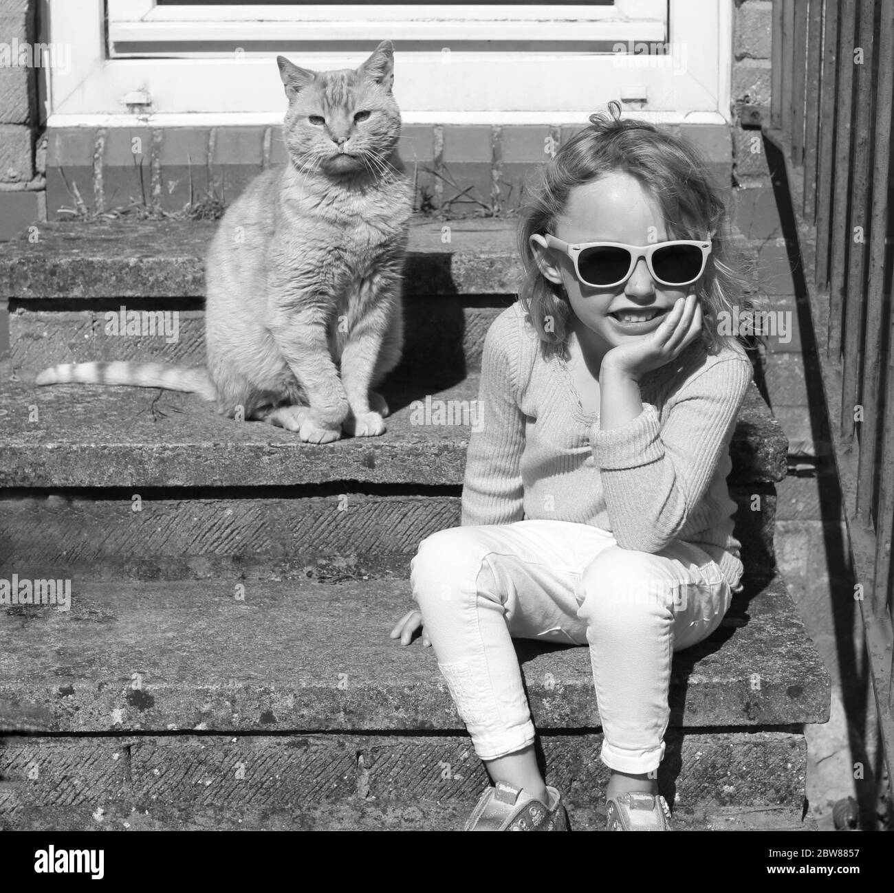 Bambino e gatto che giocano a casa. Ritratto della casa in bianco e nero Foto Stock