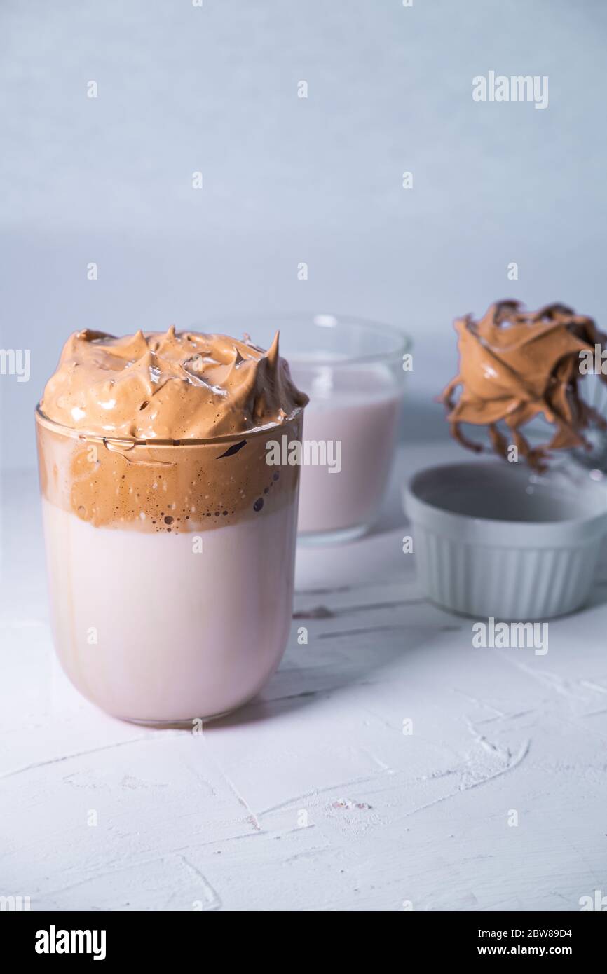 Caffè Dalgona con caffè montato e latte sullo sfondo. Bevanda alla moda coreana. Immagine verticale. Foto Stock