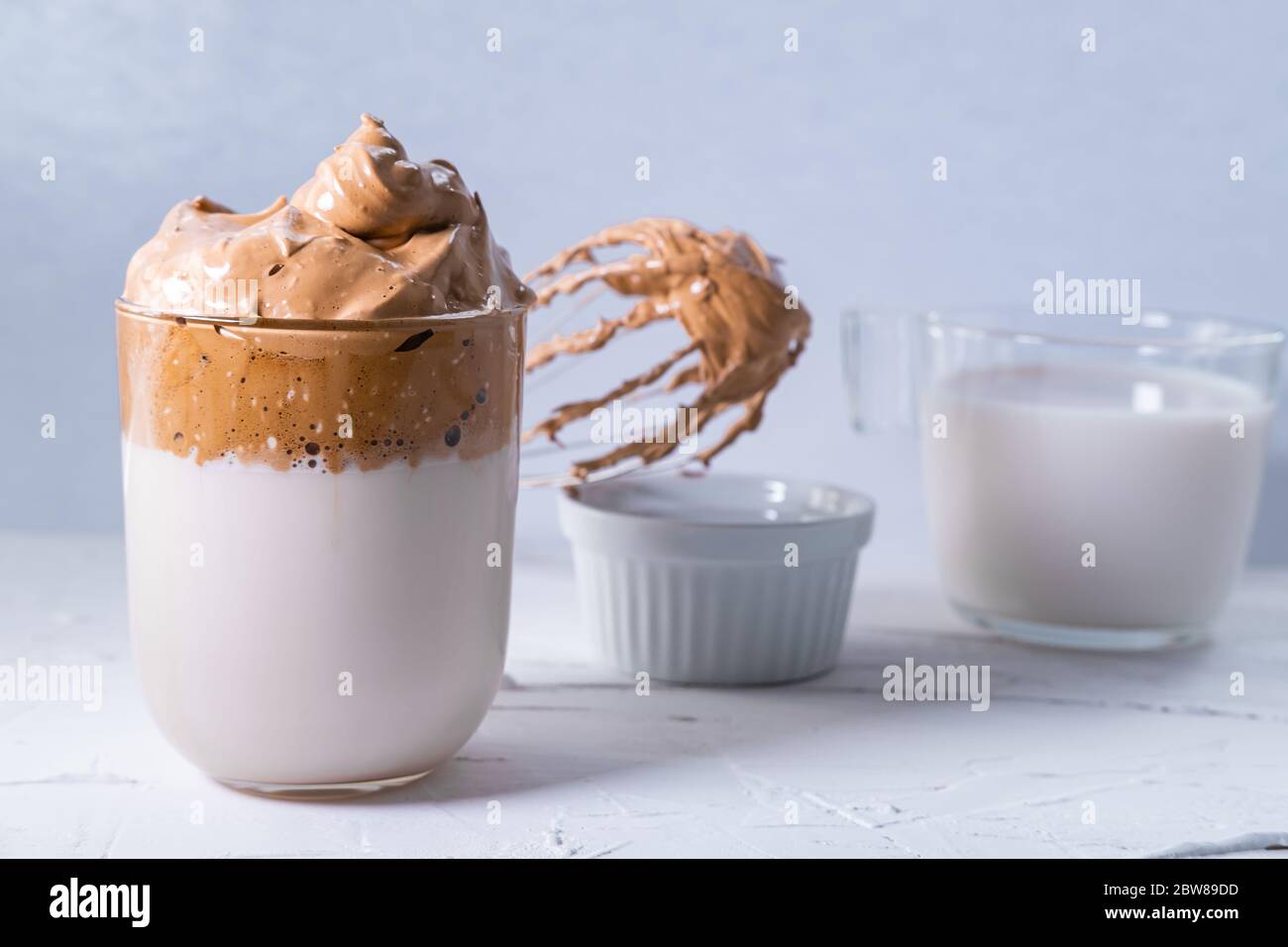 Caffè Dalgona con caffè montato e latte sullo sfondo. Caffè coreano freddo e soffice. Foto Stock