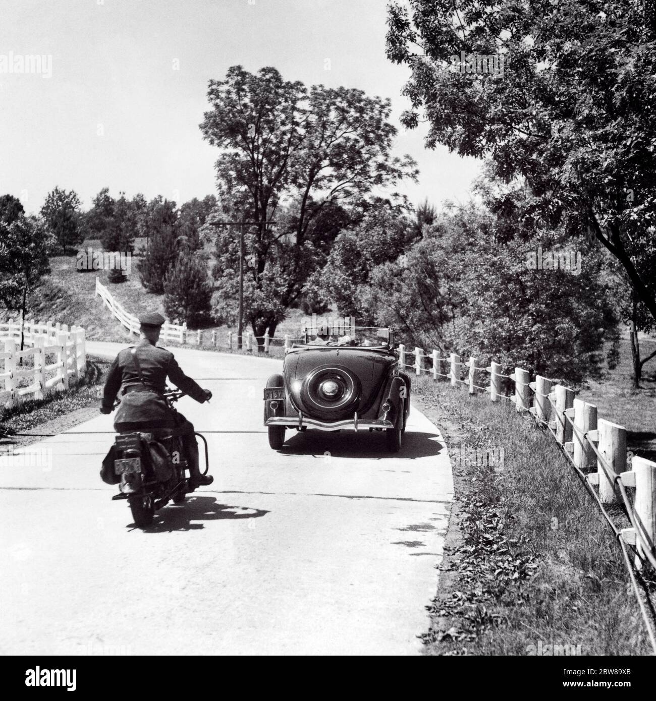 1940 ANNI 1940 UOMO AUTOSTRADA PATROL POLIZIOTTO SU MOTO CHE PERSEGUE AUTO CONVERTIBILE CON COPPIA DUE PASSEGGERI SU STRADA DI CAMPAGNA - M4762 HAR001 HARS POLIZIOTTO VEICOLO SICUREZZA STILE DI VITA VELOCITÀ FEMMINE PASSEGGERI SPAZIO RURALE COPIA MEZZA LUNGHEZZA AUTOSTRADA SIGNORE PERSONE AUTO MASCHI RISCHIO UFFICIALE TRASPORTO B&W COP PROTEGGERE E SERVIRE AVVENTURA AD ALTO ANGOLO AUTOS ECCITAZIONE POSTERIORE VISTA SULLE OCCUPAZIONI AUTORITÀ IN ACCELERAZIONE UNIFORMI PATROL CONCETTUALE DA DIETRO AUTOMOBILI VEICOLI UFFICIALI POLIZIOTTI INSEGUENDO INDIETRO VISTA INSEGUIRE COOPERAZIONI COOPERAZIONI COOPERAZIONI TOGETHERNESS BADGE NERO E BIANCO HAR001 VECCHIO STILE Foto Stock