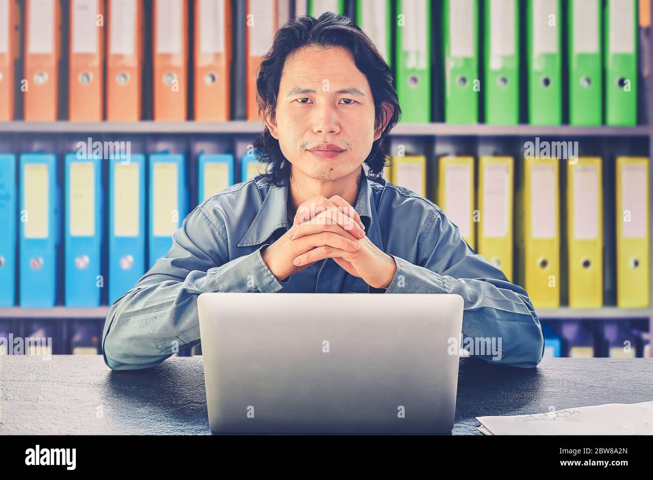 Uomo d'affari asiatico che utilizza il laptop seduto sulla scrivania guardare la determinazione della telecamera, willpower rimanere concentrato e determinato, rimanere risoluti nel perseguimento del loro Foto Stock