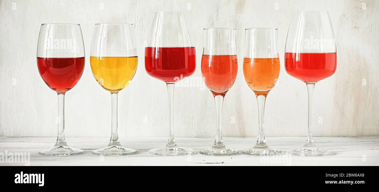 Raccolta di vari vini in un bicchiere, rosa, rosso, bianco e champagne su un tavolo rustico in legno bianco, banner. Set di vini in fila su un'annata Foto Stock