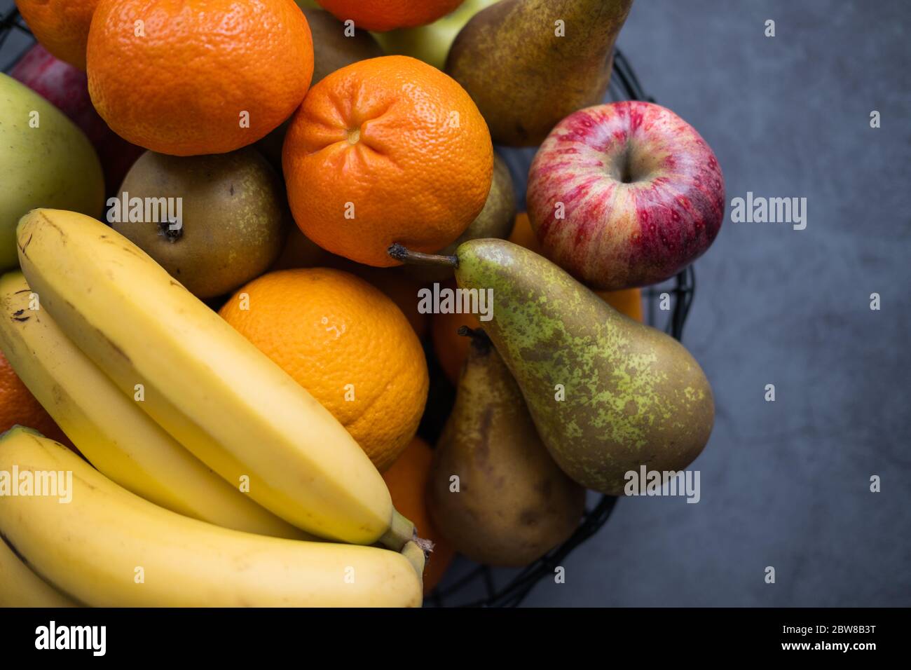 Fruterer pieno di frutta come l'arancia, la pera, la banana e la mela su fondo di cemento. Cibo sano. Vista ravvicinata. Foto Stock