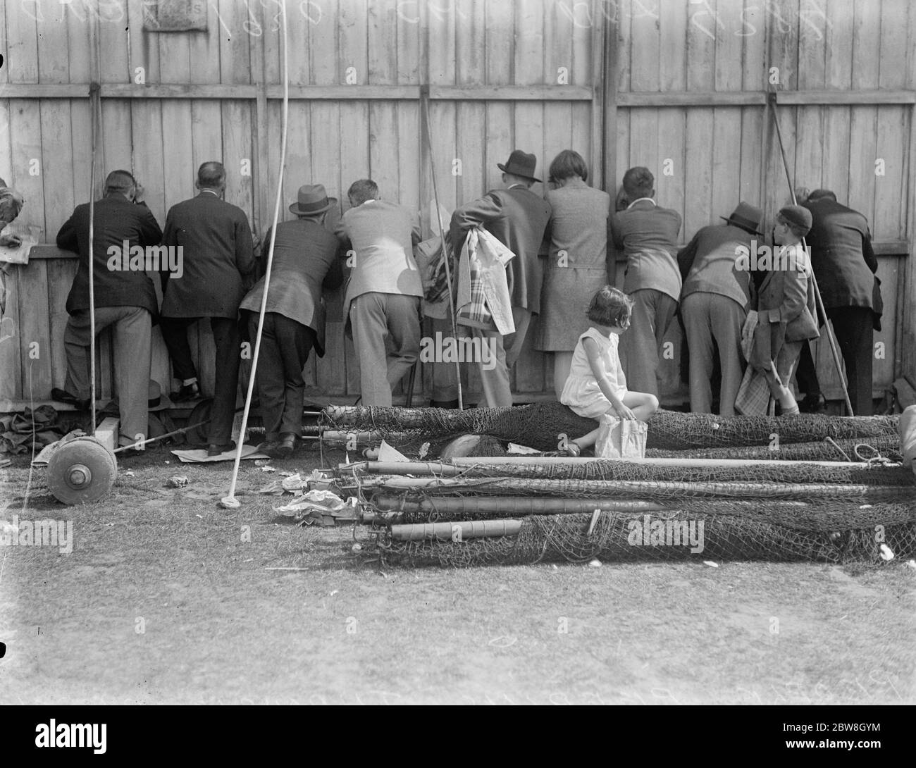 Test match , Oval , secondo giorno . Strisciare attraverso le crepe nella schermata di bowling per ottenere una visione del gioco . 1930 Foto Stock