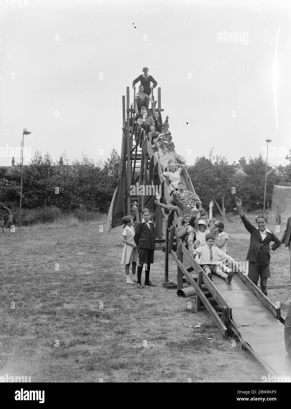 Una fila di bambini scivola giù uno scivolo . 1935 . Foto Stock