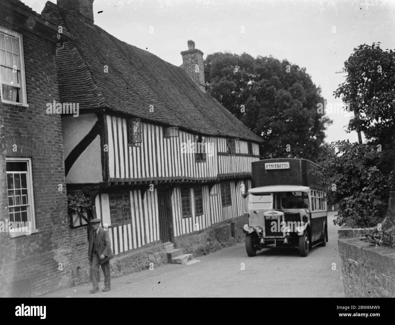 Un autobus che passa un cottage grazioso a Hollingbourne , Kent . 1935 Foto Stock