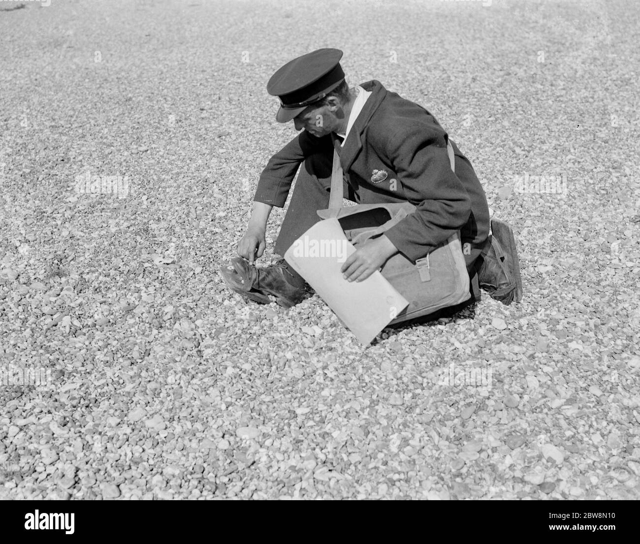 Freathy , il postino di Dungeness , indossa scarpe da spiaggia in legno per aiutarlo a camminare sui ciottoli della spiaggia di ghiaia . 1935 Foto Stock