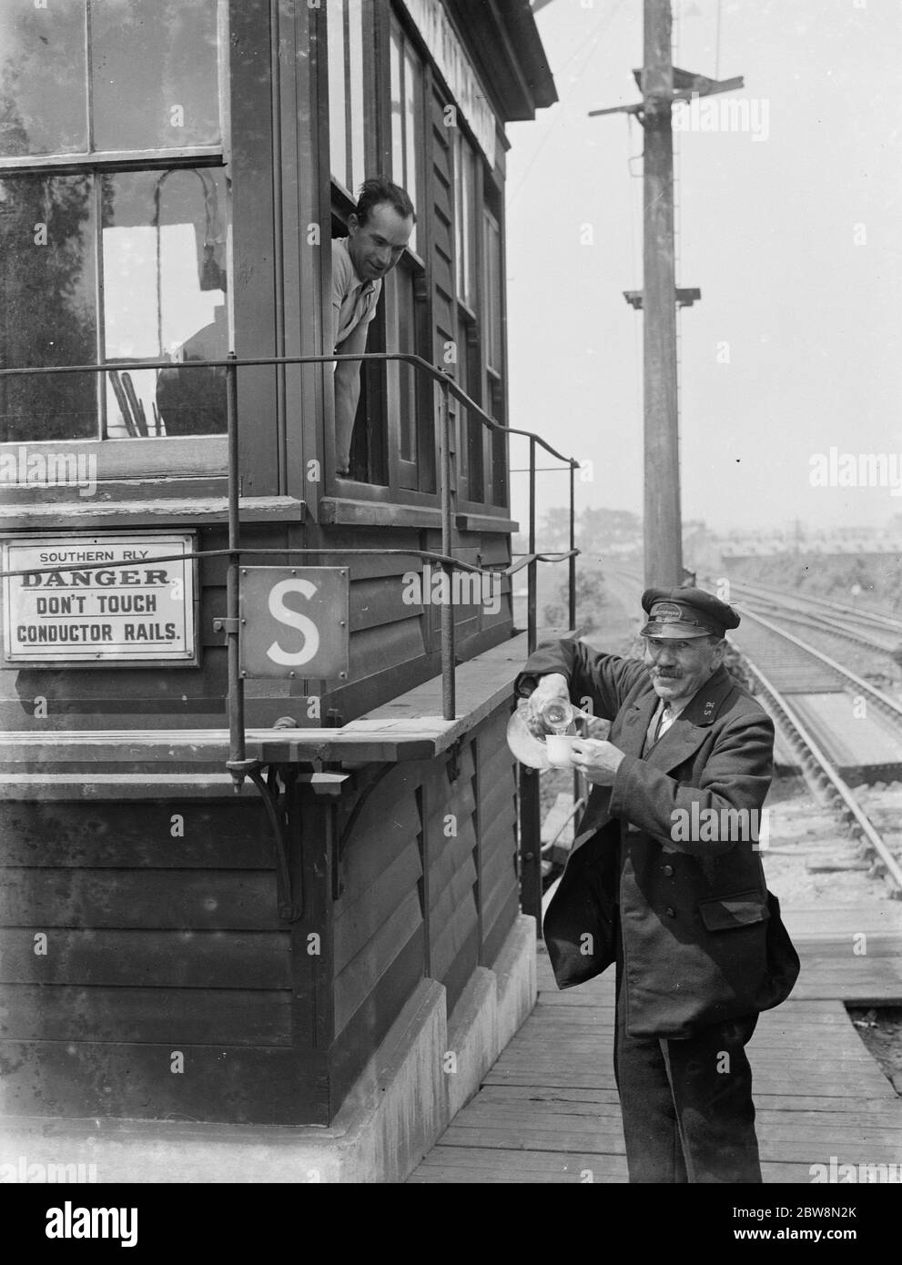 Una bevanda rinfrescante per i lavoratori ferroviari dalla scatola di segnale . 1935 Foto Stock