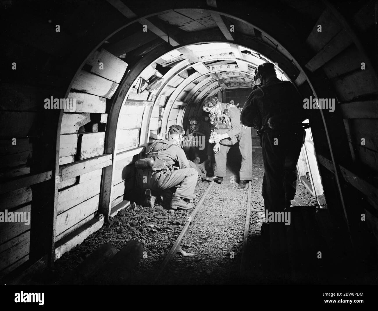 Gli uomini del Lancashire Mine Rescue Center controllano i loro dintorni mentre si muovono attraverso il pozzo della miniera . 1937 . Foto Stock