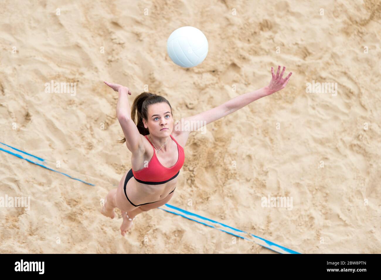 Giovane donna con palla bianca che gioca a pallavolo sulla spiaggia. Vacanza estiva e concetto sportivo Foto Stock