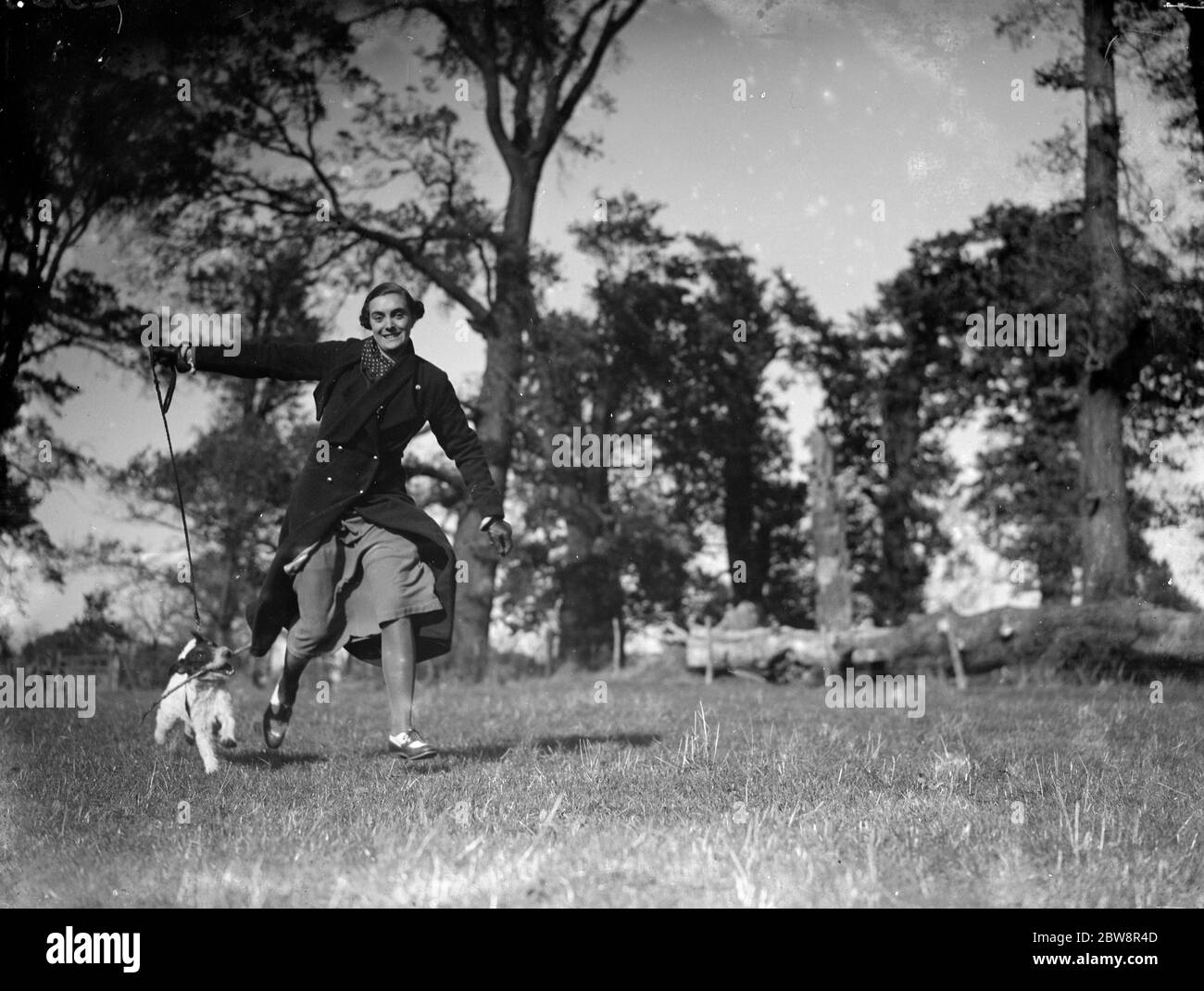 Muriel con il suo terrier 'Cinders' che corre nel parco. 1936 Foto Stock