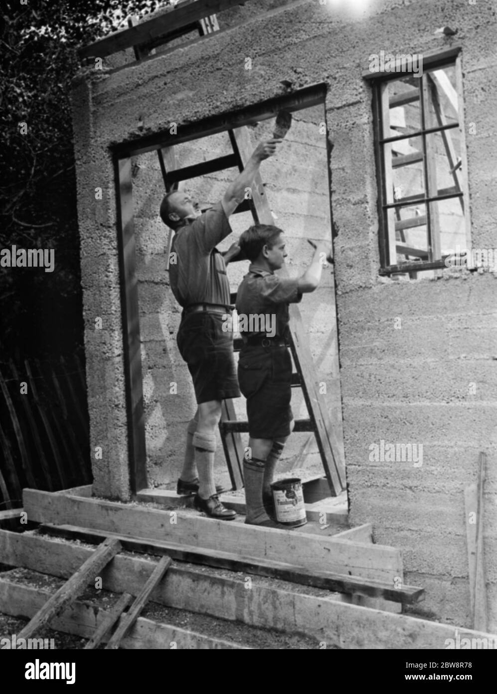 Gli scout Bridgen costruiscono la loro propria sede . Con la guida di un'aldulta , uno scout sta dipingendo un telaio della porta . Foto Stock