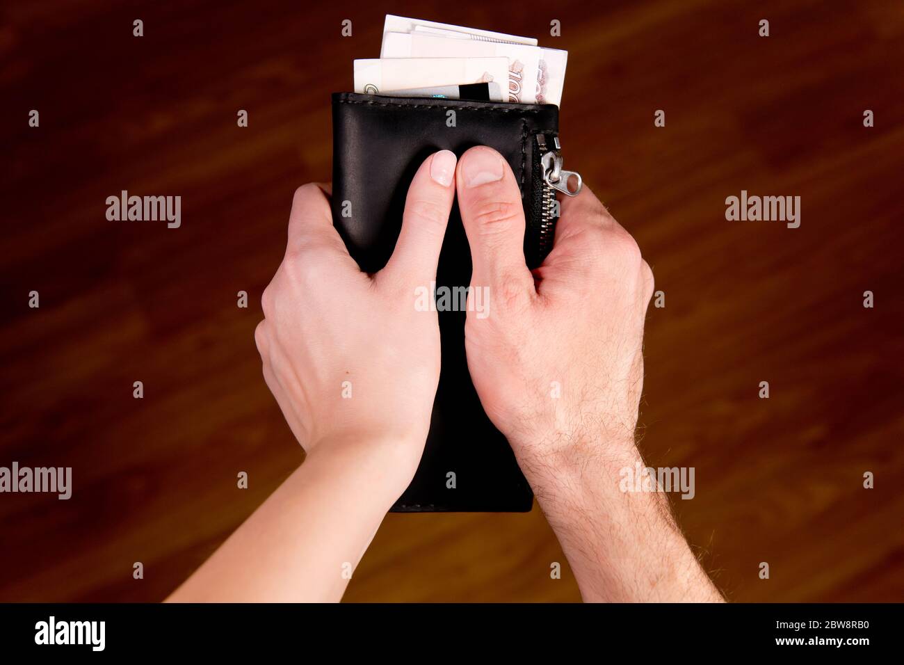 le mani maschili e femminili tengono un portafoglio come un simbolo del bilancio globale Foto Stock