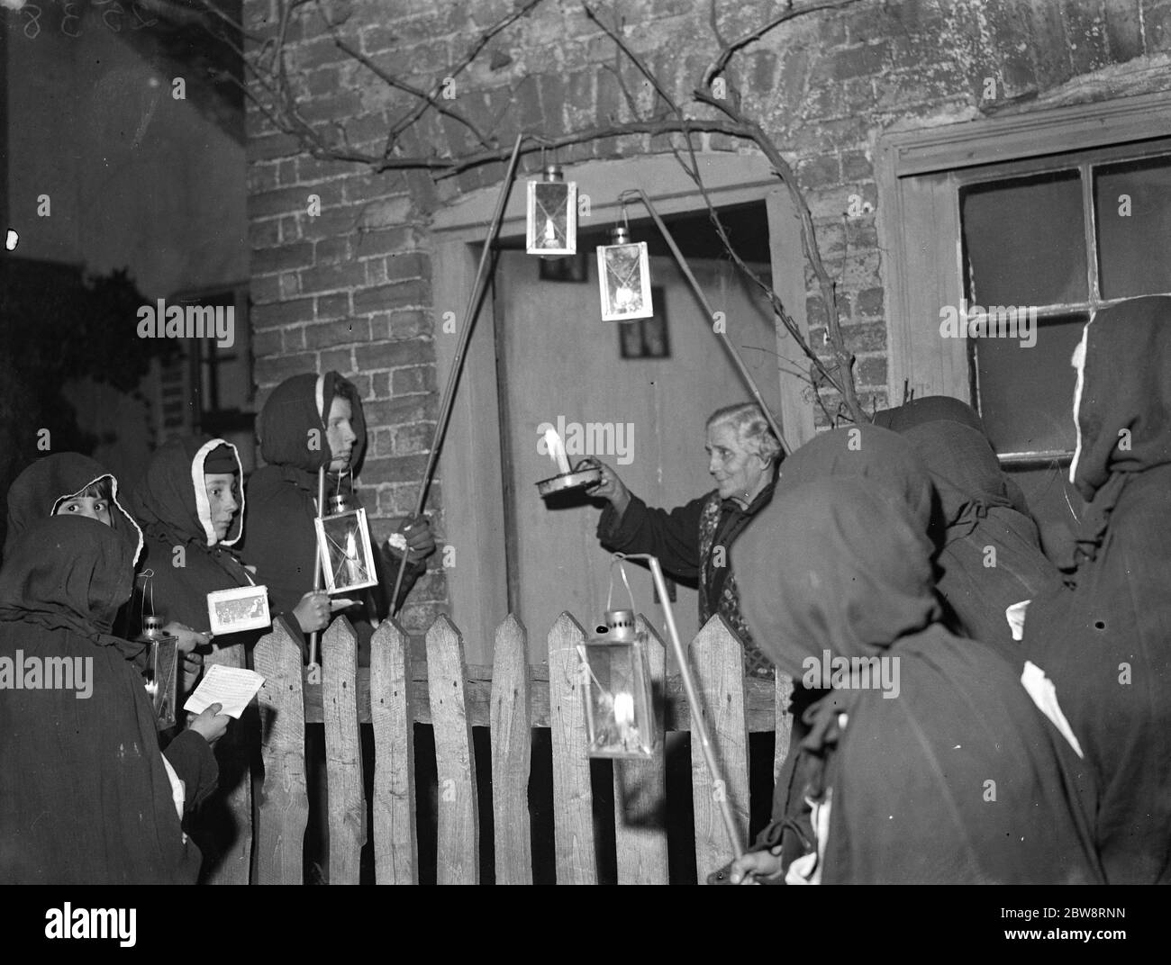 Un residente di Eynsford ha una visita da cantanti di carol agganciati . 1935 Foto Stock
