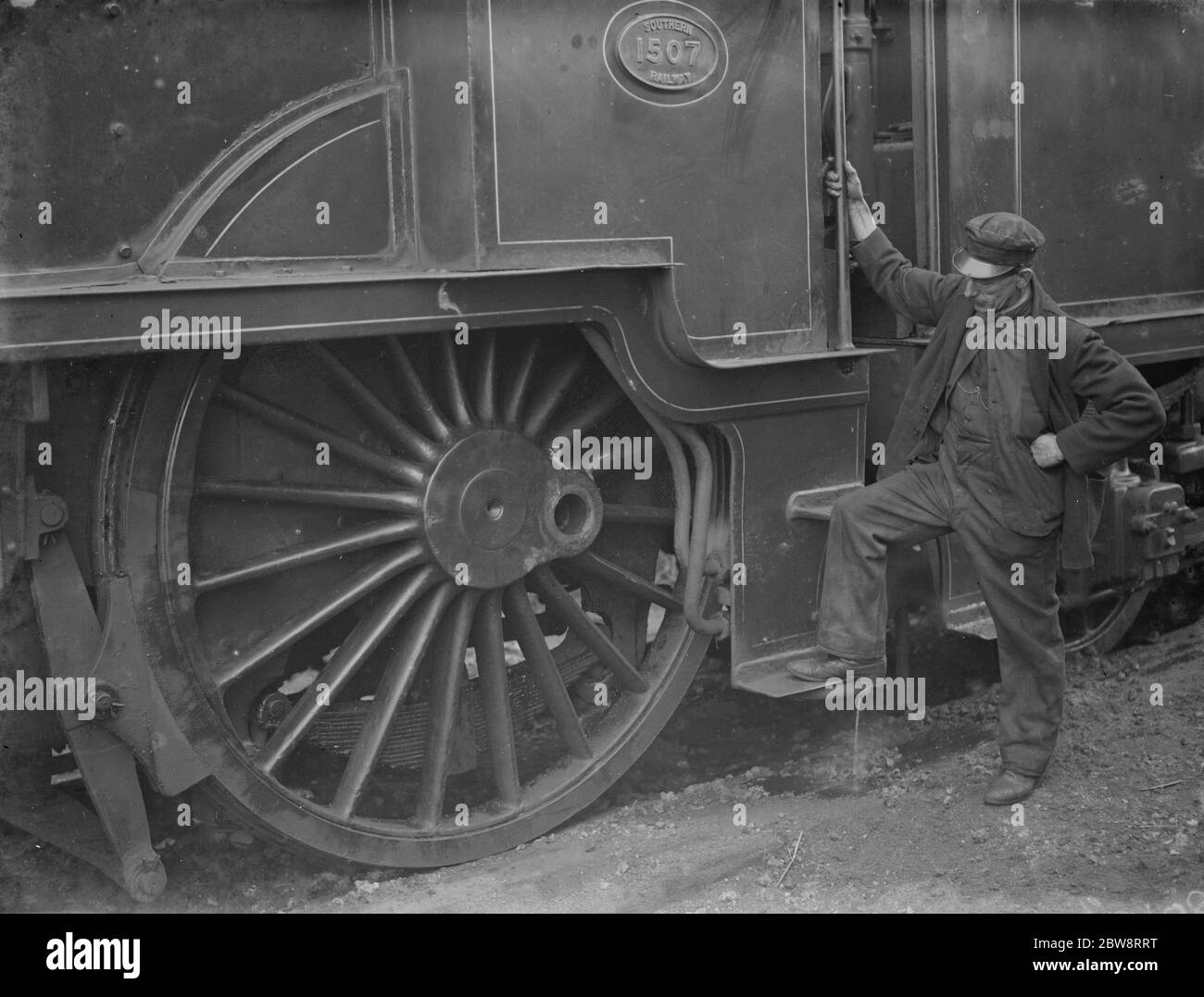 Un ingegnere del treno guarda una delle grandi ruote del motore dopo essere stato deragliato a Swanley , Kent . 1938 Foto Stock