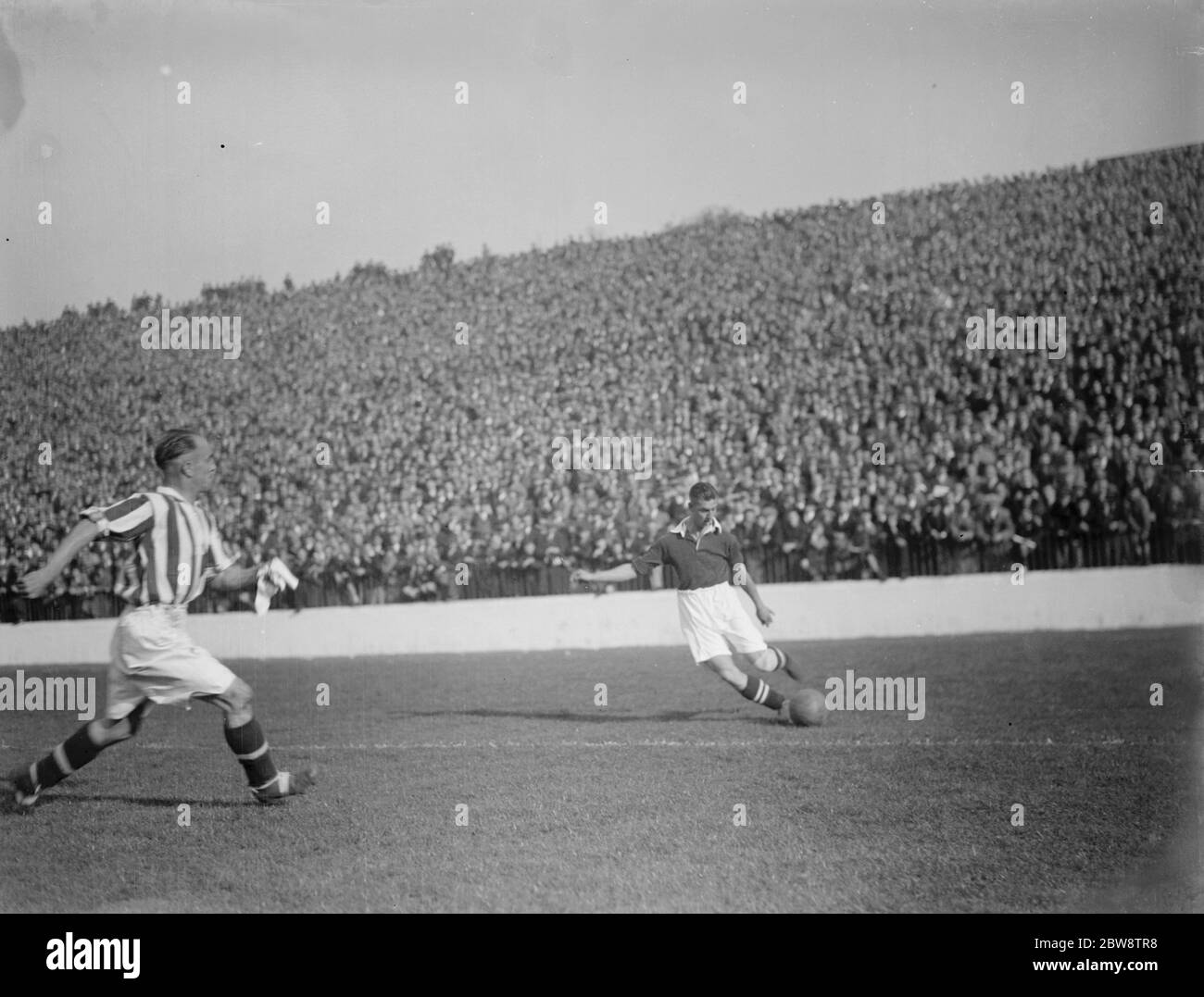 Il giocatore di Charlton Athletic Football Club, Harold Hobbis , si allinea per una croce davanti a un difensore . 1936 Foto Stock