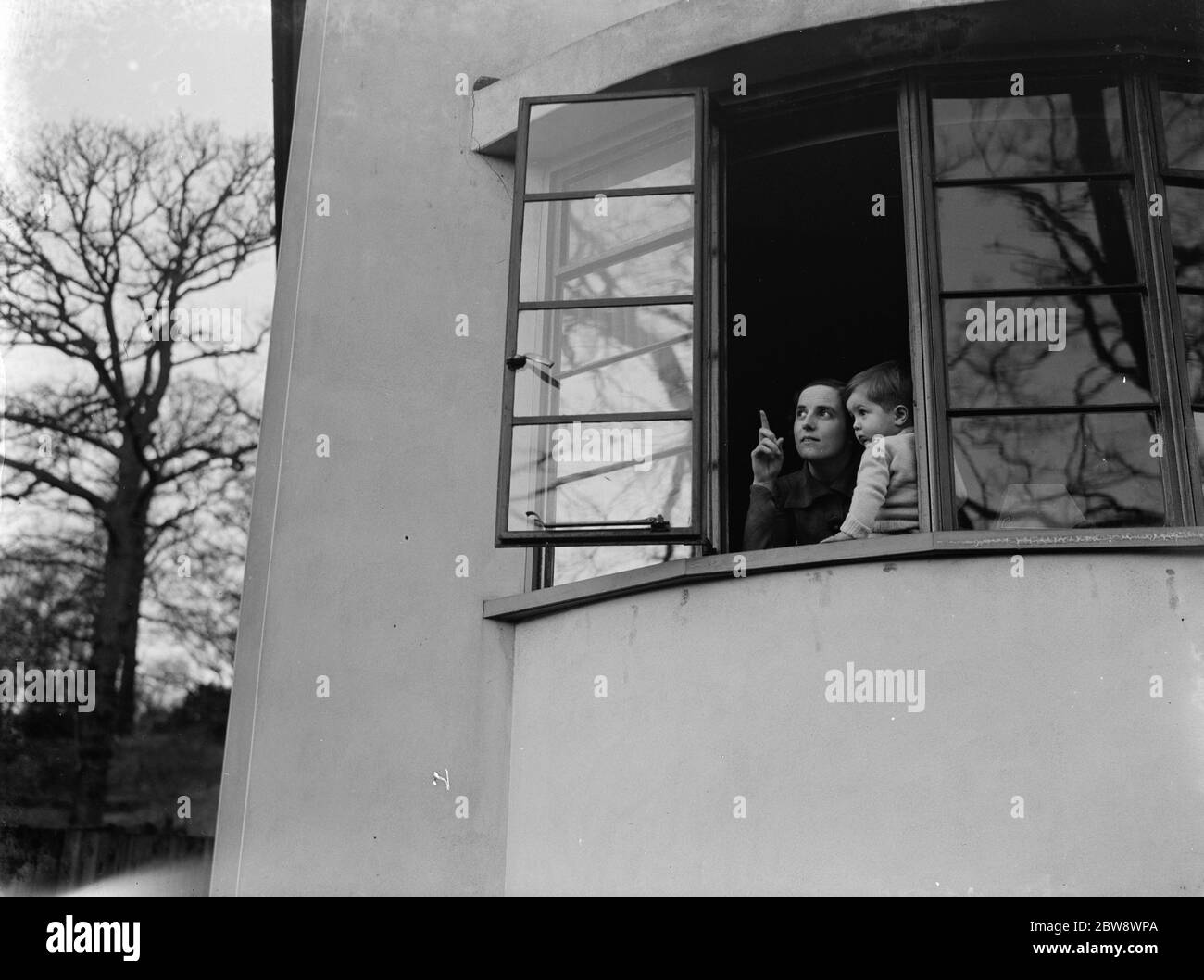 La signora Zehnder con il suo ragazzino , guardando fuori dalla finestra di casa sua . Scatti pubblicitari effettuati per il Daily Mirror . 1937 Foto Stock