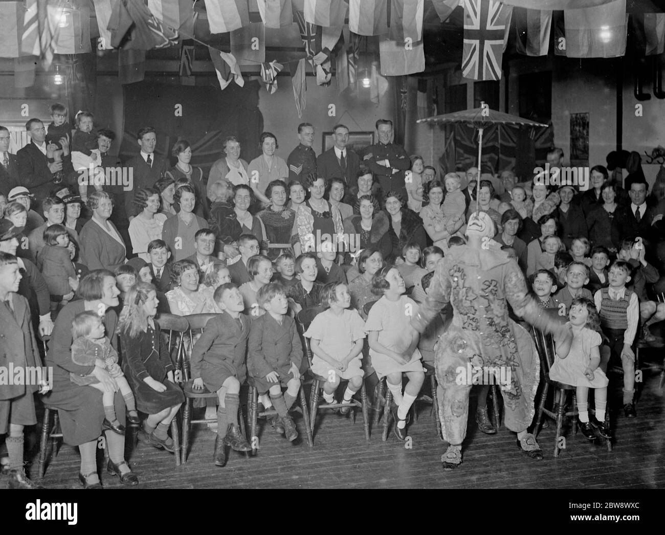I bambini si divertono mentre un clown bilancia un ombrello sul naso alla festa dei bambini dell' esercito territoriale a Orpington , Kent . 1936 Foto Stock