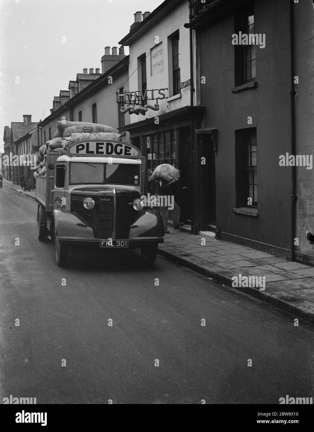 I lavoratori scaricano sacchi di farina da un camion Bedford appartenente alla Pedge & Son Ltd , la società di macinazione , su una delle loro consegne ad Ashford, Kent . 1939 Foto Stock